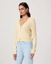 Woman wearing a light yellow cardigan by Paige and light blue jeans on a white background side view