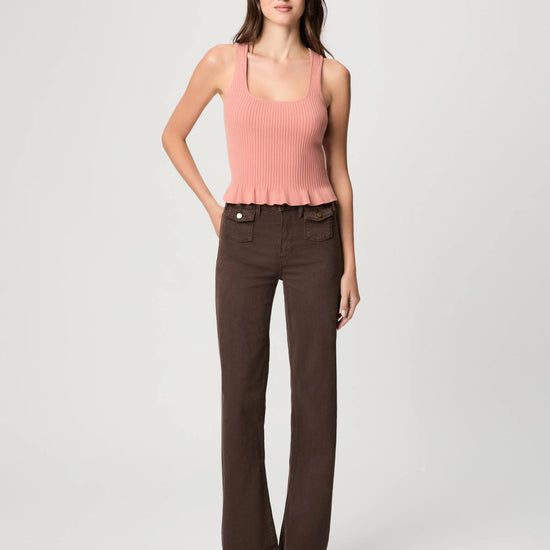 Woman wearing a pink sleeveless top and brown pants by Paige on a white background