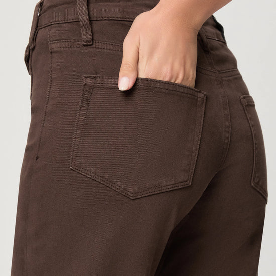 Brown pants with a pocket, worn by a person, on a plain background close up