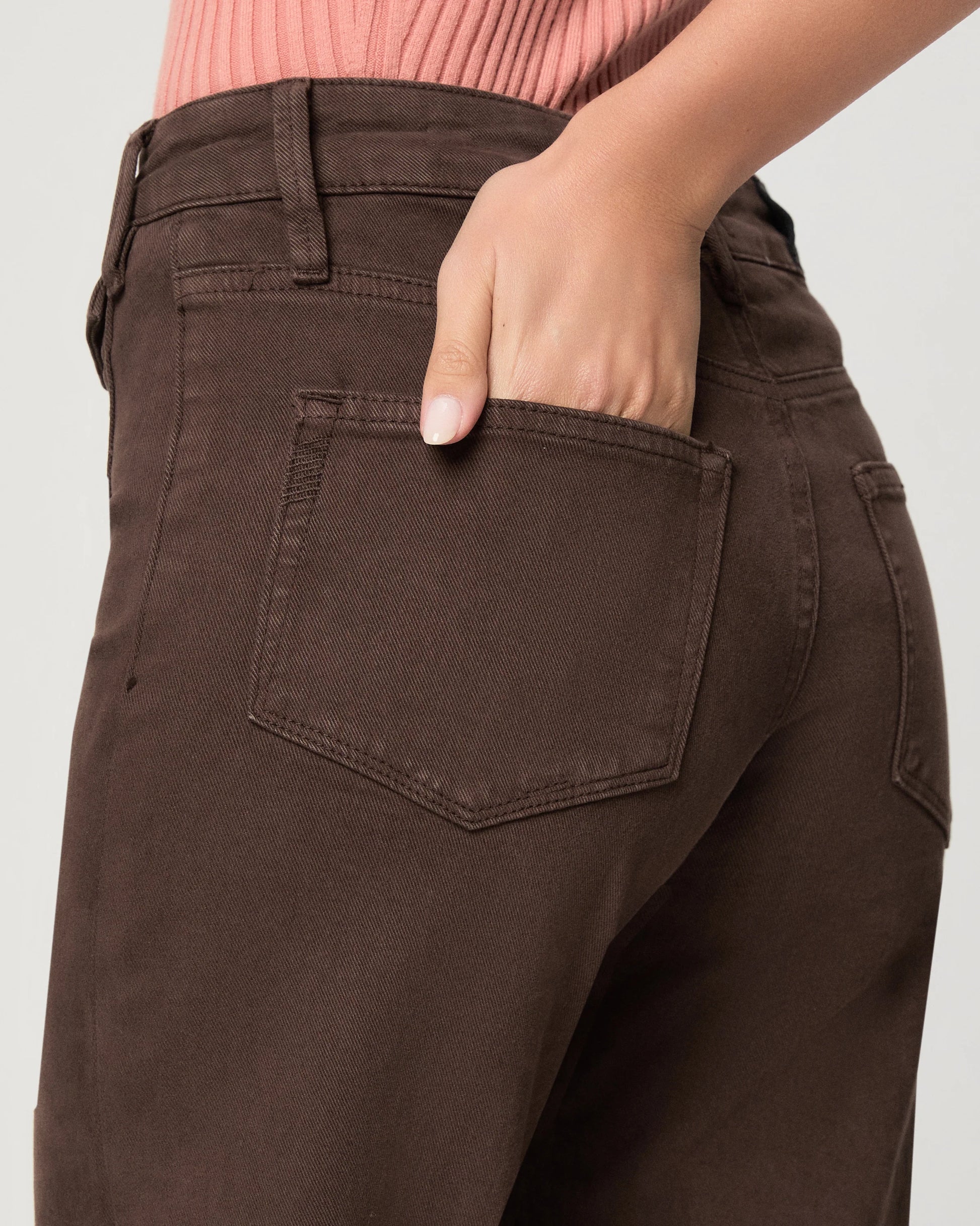 Brown pants with a pocket, worn by a person, on a plain background close up