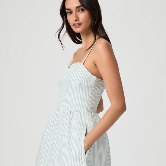 Woman wearing a light blue ribbed dress against a white background