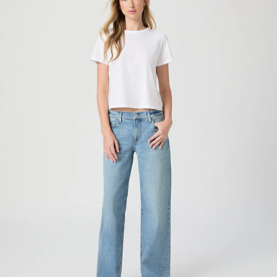 Woman wearing a white t-shirt and light blue jeans on a white background from Paige