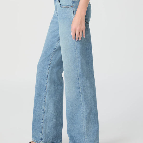 Light blue jeans worn by a person on a white background from Paige