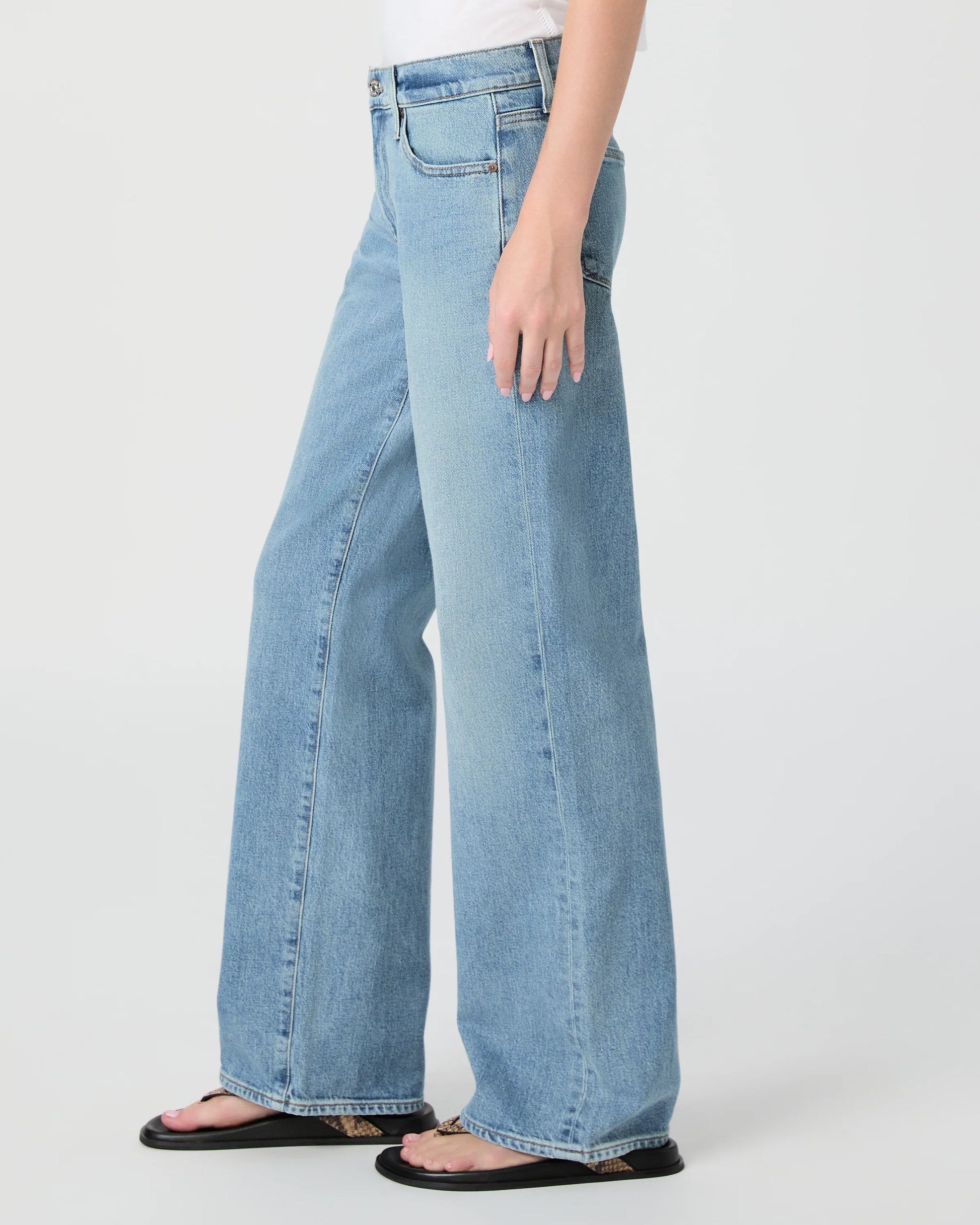Light blue jeans worn by a person on a white background from Paige
