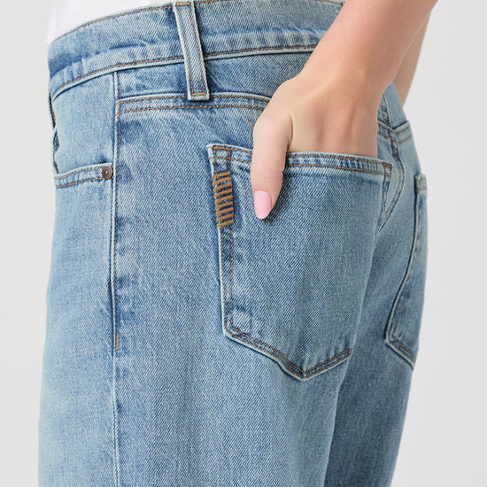 Close-up of a person wearing light blue jeans with a white background from paige