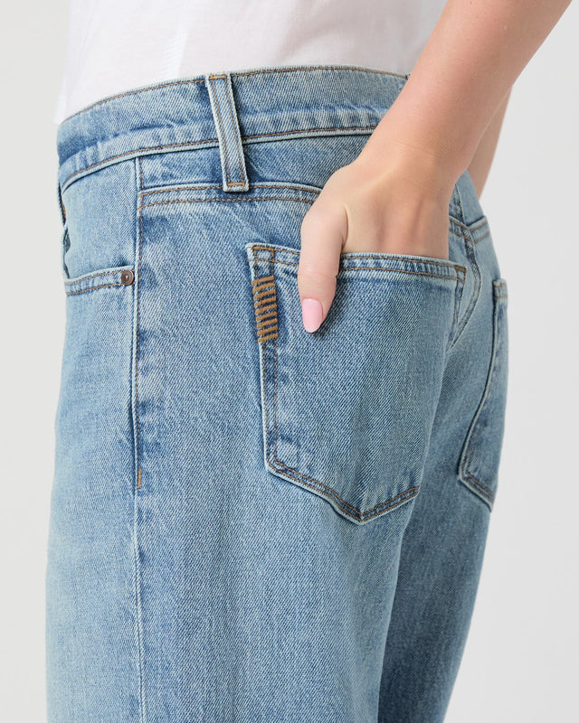 Close-up of a person wearing light blue jeans with a white background from paige