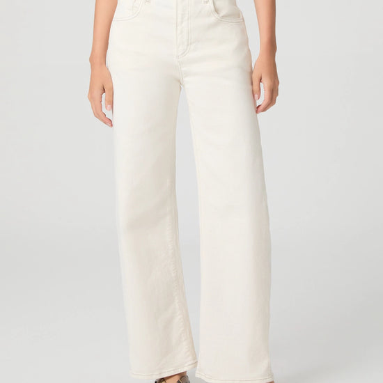 Person wearing white Paige jeans on a plain background