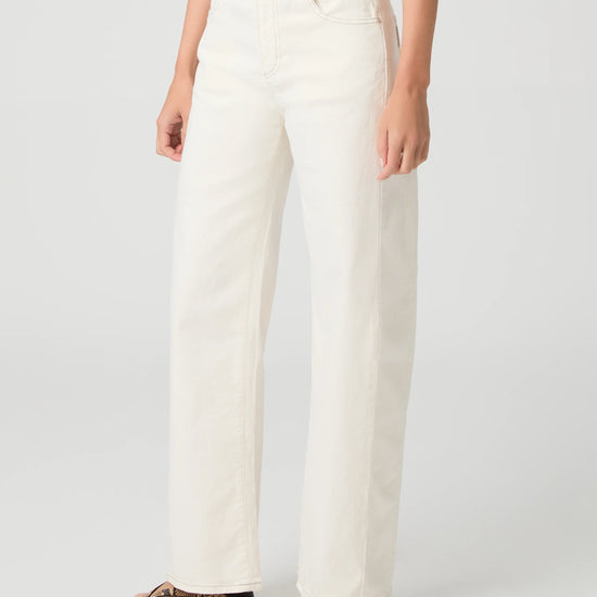 Person wearing white Paige jeans on a plain background side view