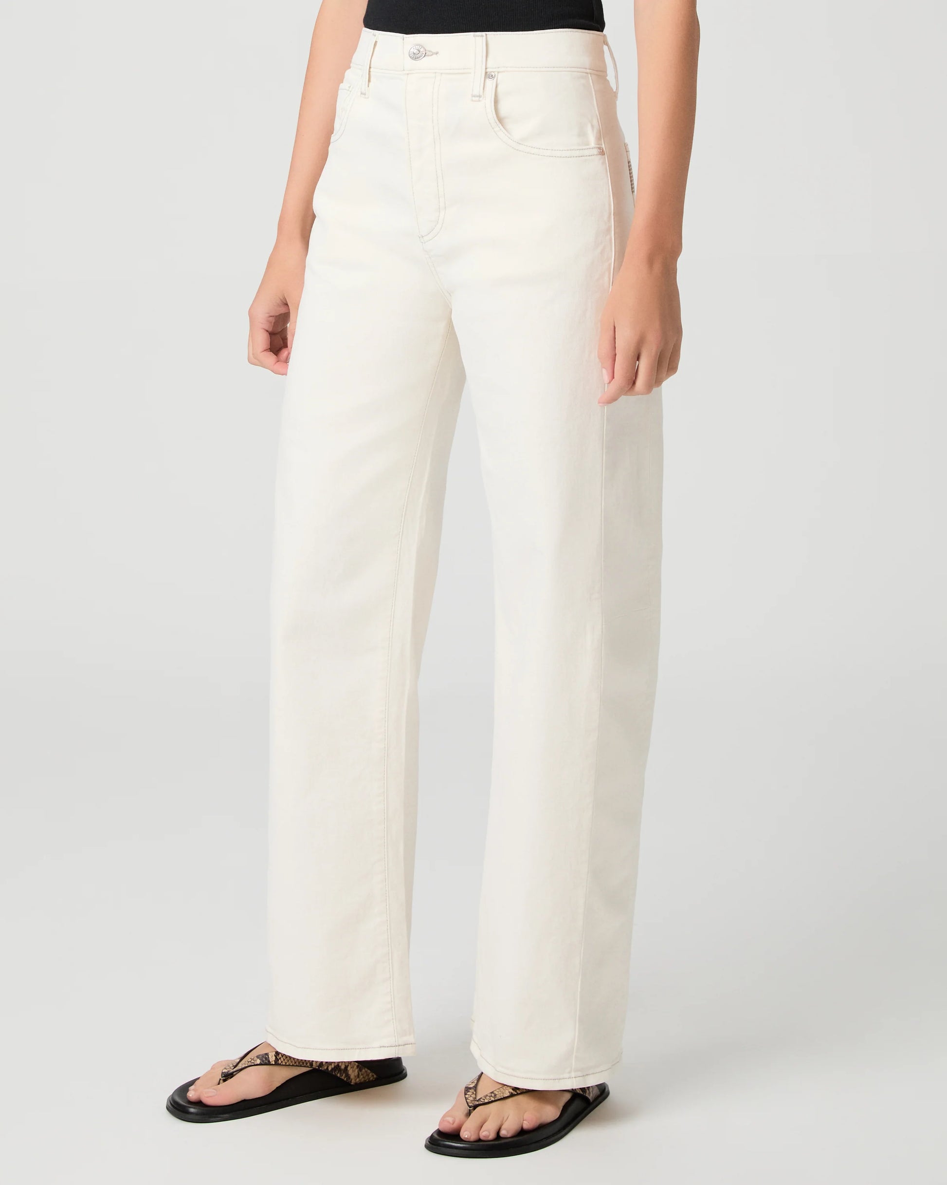 Person wearing white Paige jeans on a plain background side view