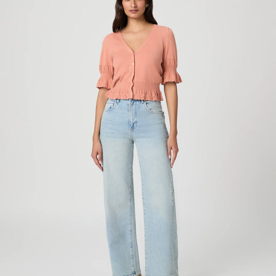 Woman wearing a pink blouse and light blue jeans on a white background