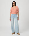 Woman wearing a pink blouse and light blue jeans on a white background