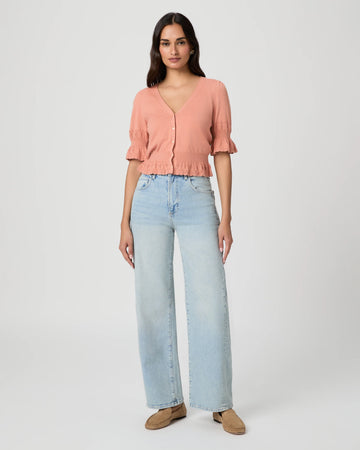 Woman wearing a pink blouse and light blue jeans on a white background