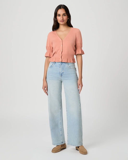 Woman wearing a pink blouse and light blue jeans on a white background