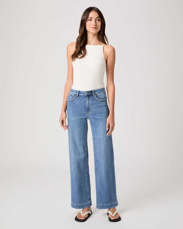 Woman wearing blue jeans and a white top on a plain background