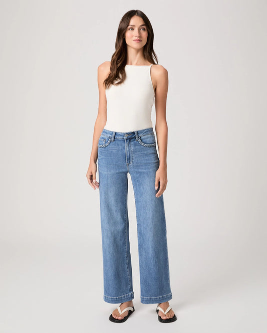 Woman wearing blue jeans and a white top on a plain background