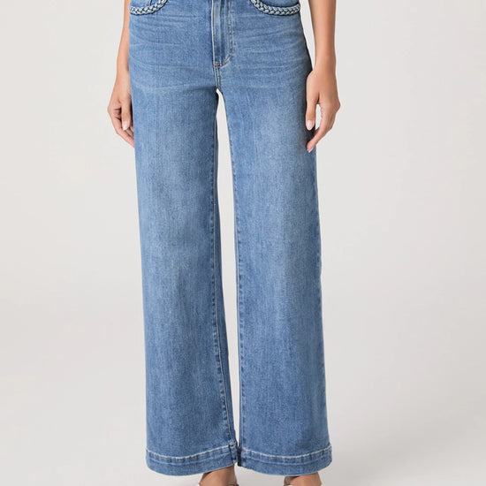 Person wearing blue jeans with embellished waistband on a white background