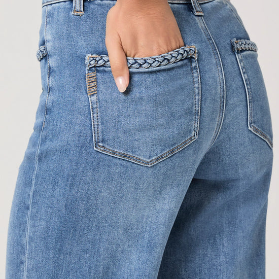 Close-up of blue jeans with decorative stitching on a plain background