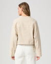 Rear view of model wearing a beige jacket and white pants on a light gray background from Paige