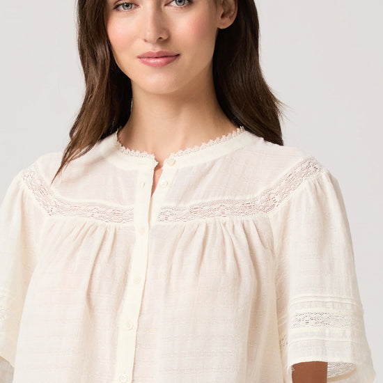 Woman wearing a white blouse by Paige on a plain background close up 