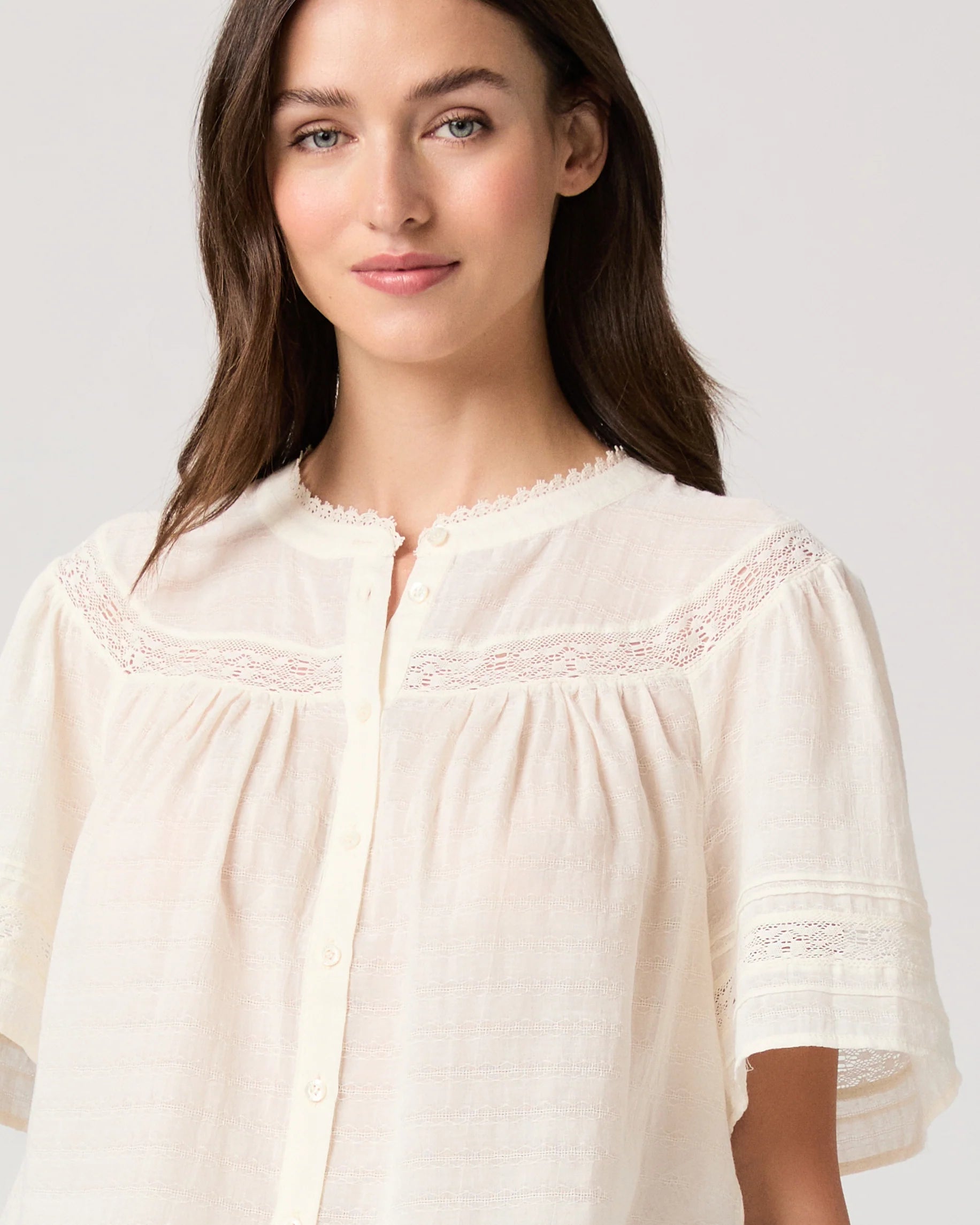 Woman wearing a white blouse by Paige on a plain background close up 