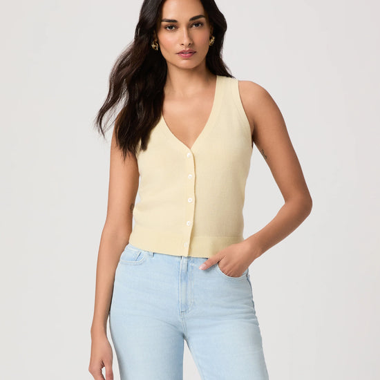 Woman wearing a light yellow sleeveless Paige top and light blue jeans on a plain background