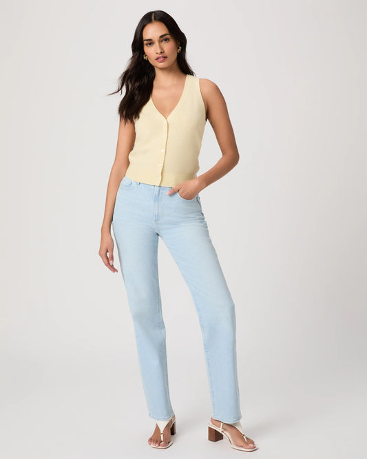 Woman wearing a light yellow sleeveless Paige top and light blue jeans on a plain background, showing full outfit
