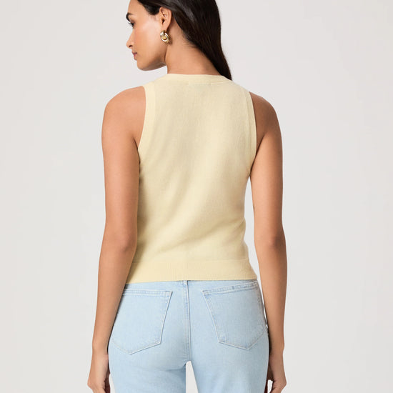 Woman wearing a light yellow sleeveless Paige top and light blue jeans on a plain background rear view