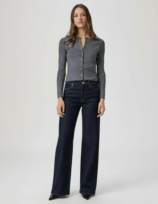 Woman wearing a gray cardigan and dark denim wide leg jeans on a white background