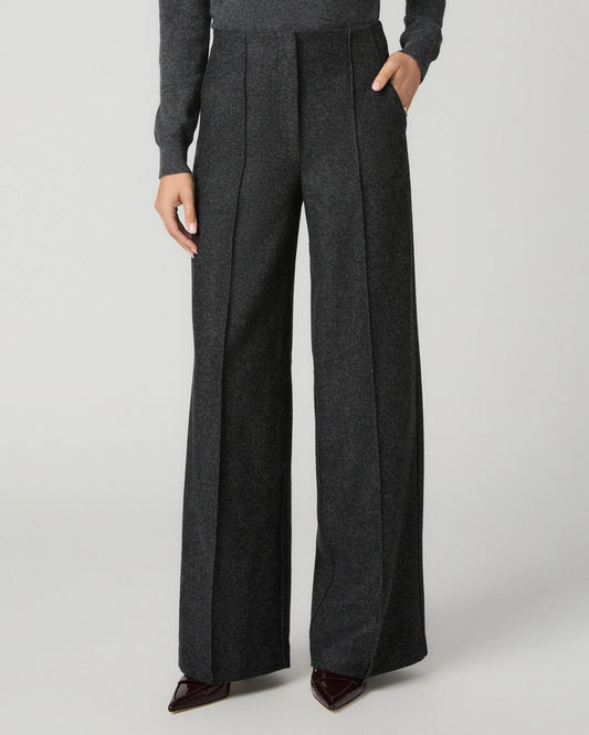 A model wearing dark gray wide-leg pleated trousers with a matching gray long-sleeve top and dark brown pointed-toe heels, shown from the waist down on a light gray studio background.