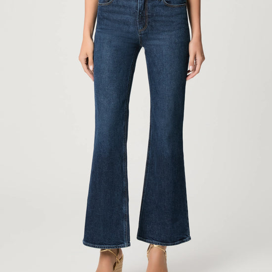 Person wearing blue flared jeans on a white background