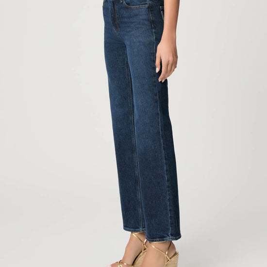 Person wearing blue jeans and gold sandals on a white background