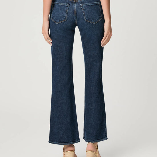 Person wearing dark blue flared jeans on a white background