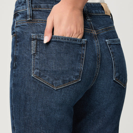 Close-up of blue jeans with a hand in the pocket on a light gray background