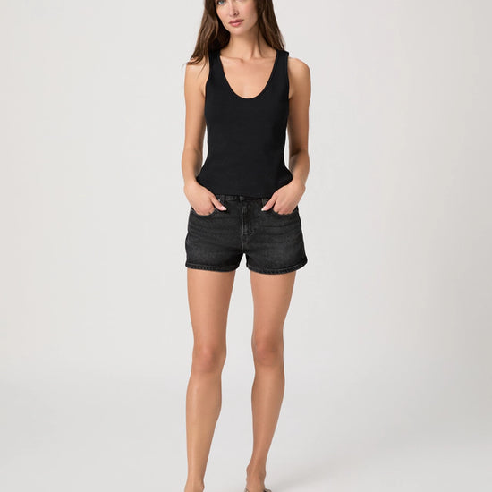 Woman wearing a black tank top and black shorts on a white background