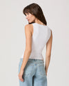 Woman wearing a white sleeveless top and light blue jeans on a plain background