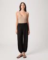 Woman wearing a beige tank top and black wide-leg pants on a white background
