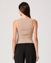 Woman wearing a beige sleeveless top and black pants on a light gray background