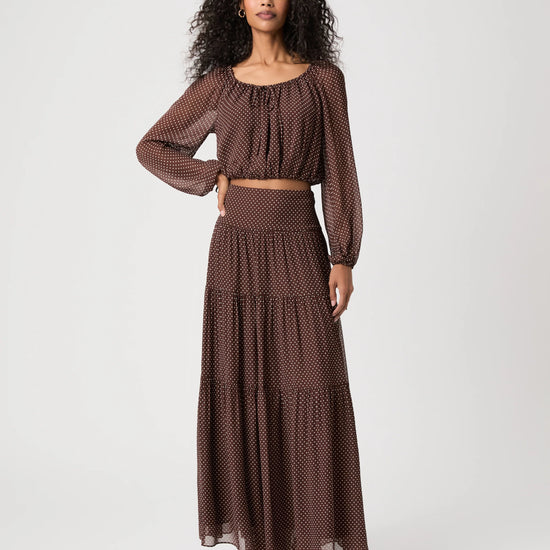 Woman wearing spotty brown and cream blouse and matching skirt on white background