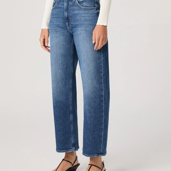 Person wearing blue jeans on a plain background