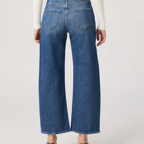 Person wearing blue jeans on a plain background