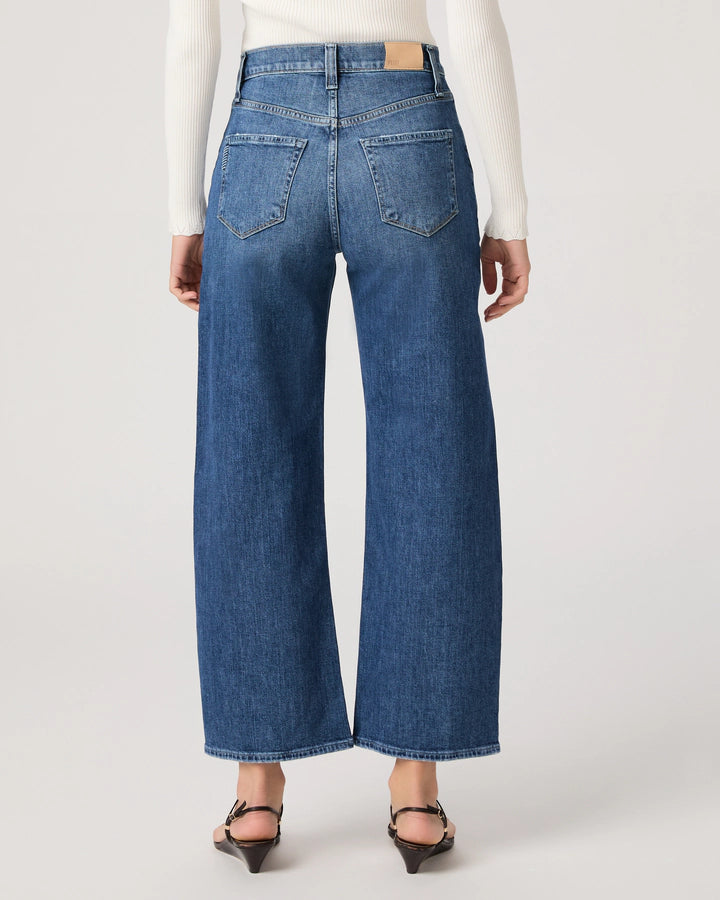 Person wearing blue jeans on a plain background