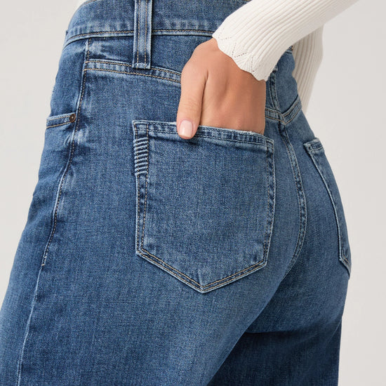 Close-up of blue jeans with a white sweater background