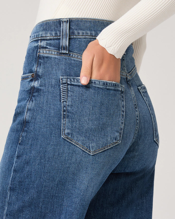 Close-up of blue jeans with a white sweater background