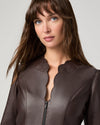 A close-up shot of a woman wearing a dark brown faux-leather jacket with a unique scalloped collar and a front zipper, set against a plain light gray background.