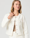 Woman wearing a cream Paige denim jacket and shorts on a plain background close up