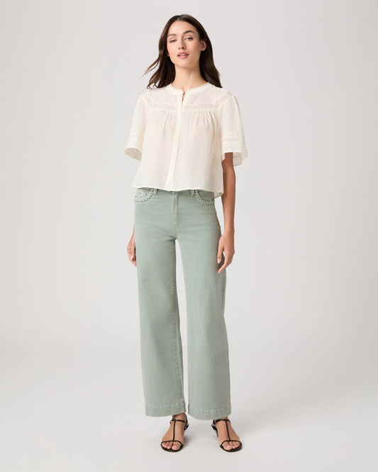 Woman wearing a white blouse and light green pants on a white background