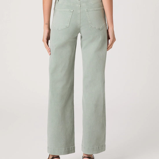Person wearing light green wide-leg jeans on a white background