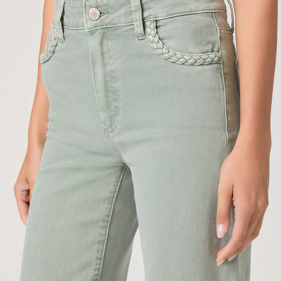 Light green jeans with braided detail on a plain background