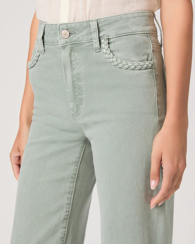 Light green jeans with braided detail on a plain background