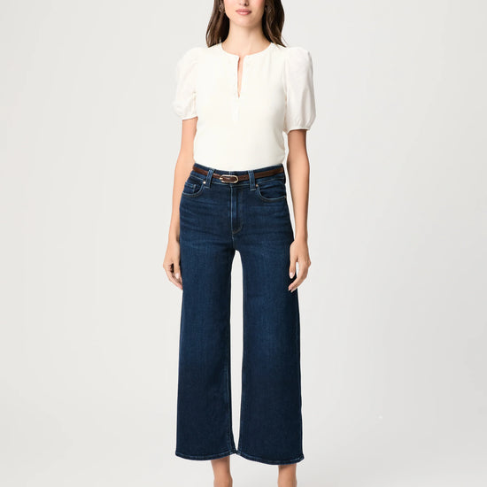 Woman wearing a white top and dark blue jeans on a white background